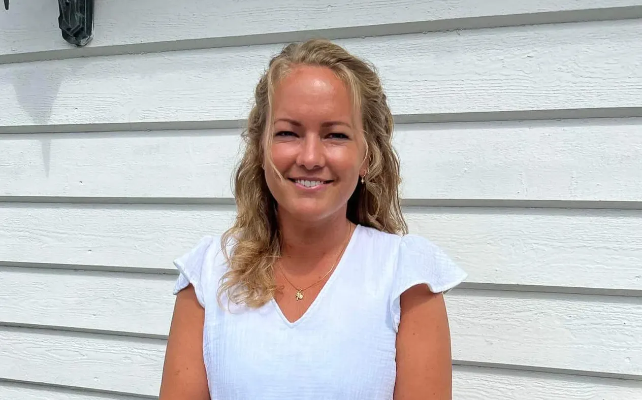 Sunniva smiler foran en hvit trevegg.